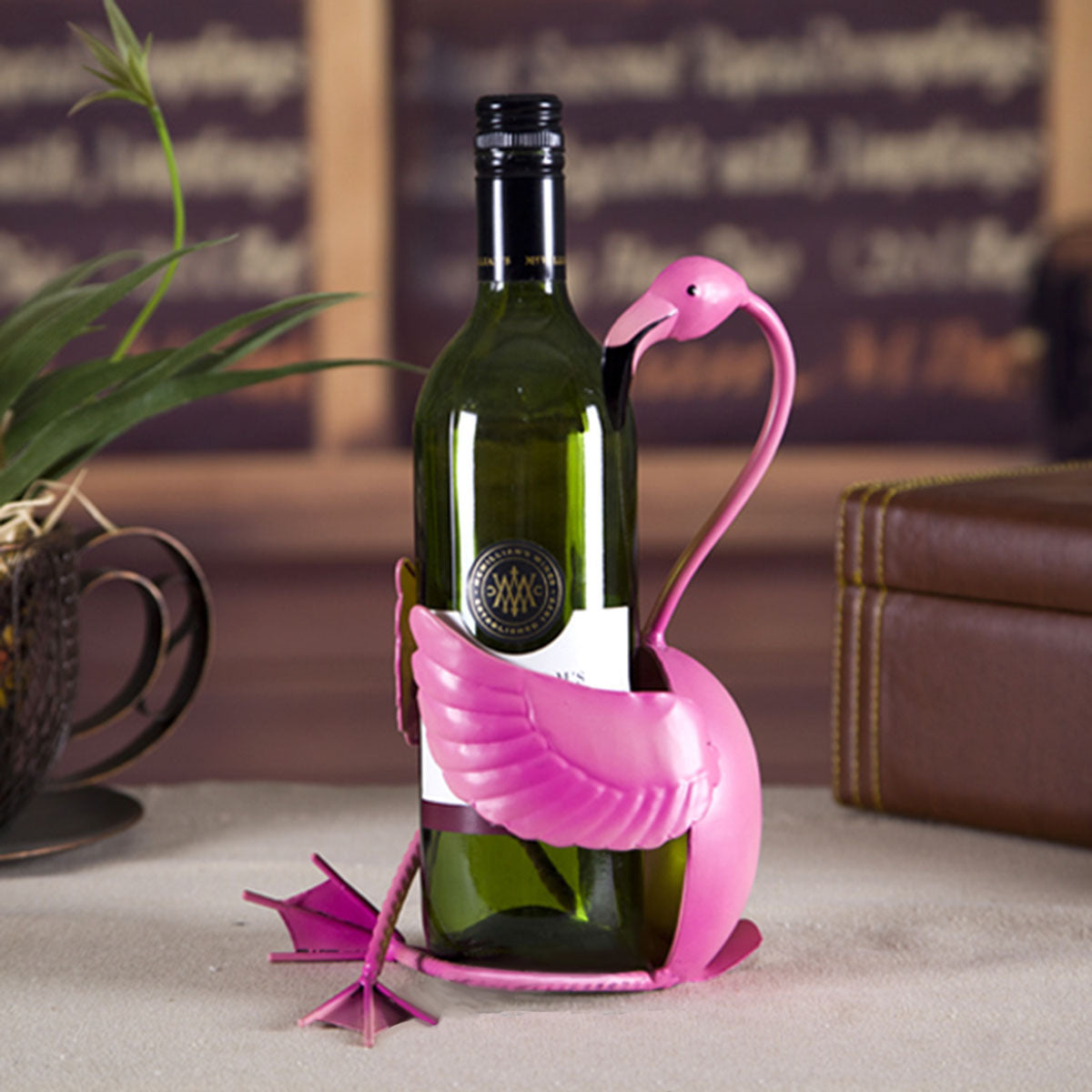 Pink flamingo-shaped wine bottle holder with a wine bottle on a table.