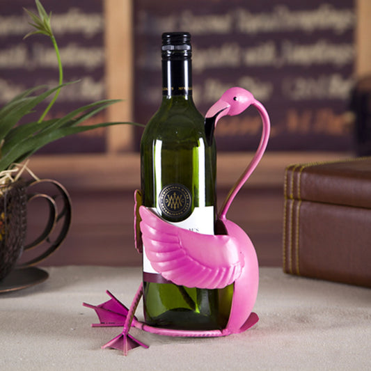 Pink flamingo-shaped wine bottle holder with a wine bottle on a table.