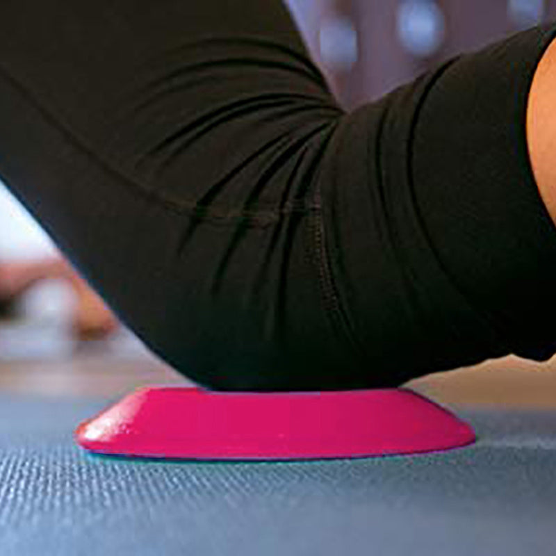 Person using a pink foam roller on a yoga mat