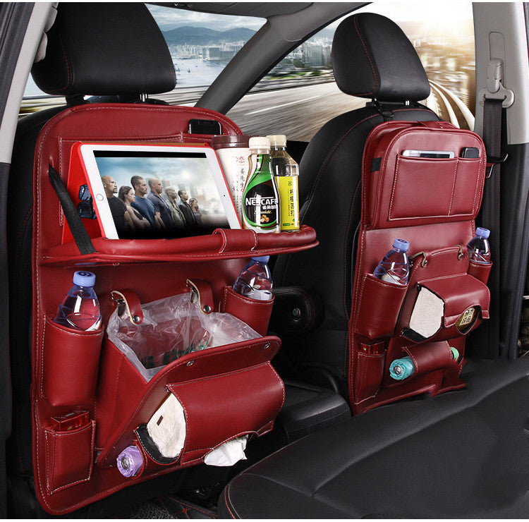Red car seat organizer with multiple pockets and a screen displaying a movie, with a scenic road view outside.