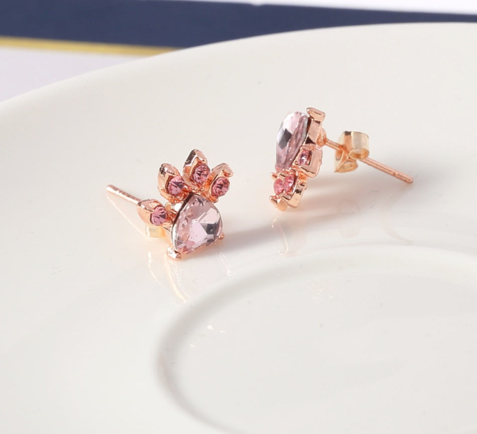 Rose gold earrings with pink gemstones on a white surface