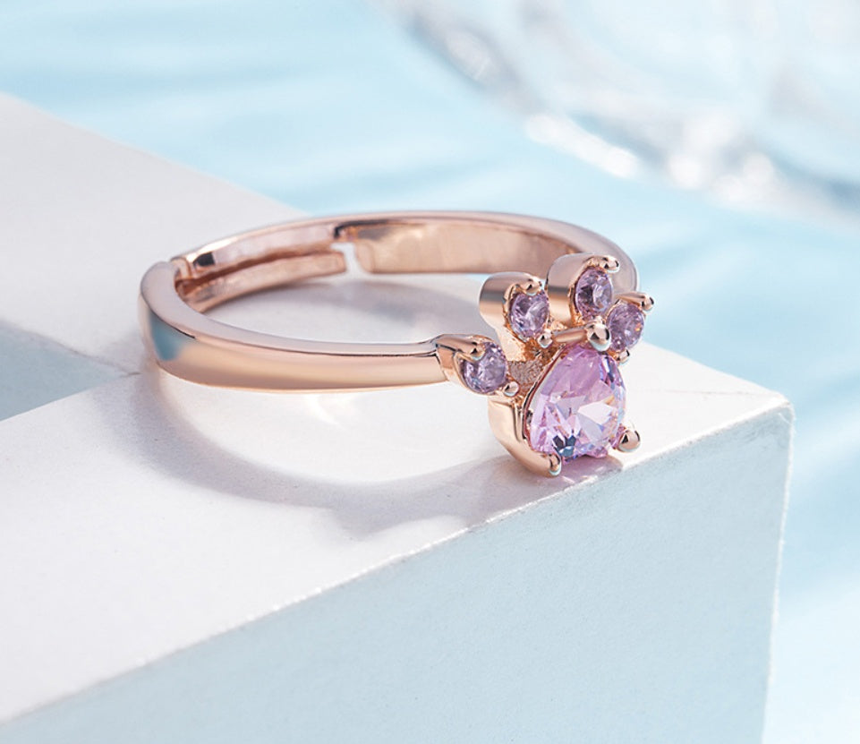 Rose gold ring with pink gemstones on a light blue background