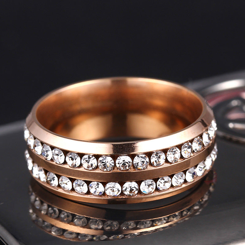 Rose gold ring with crystal stones on a reflective surface