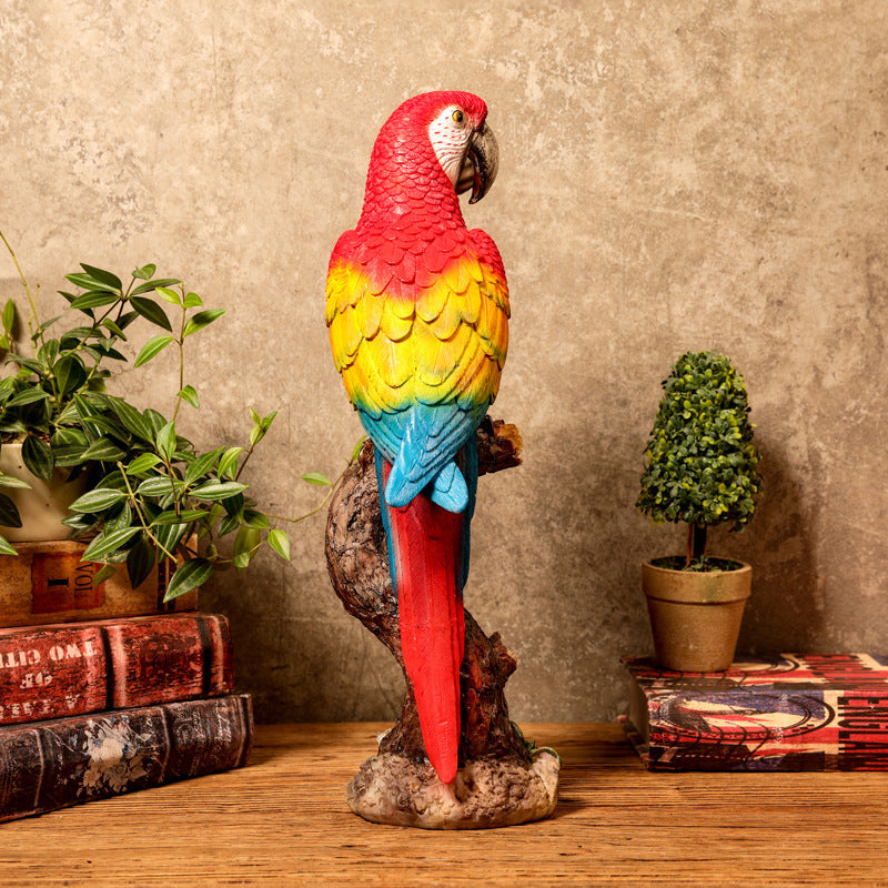 Colorful parrot statue on a wooden surface with books and plants in the background