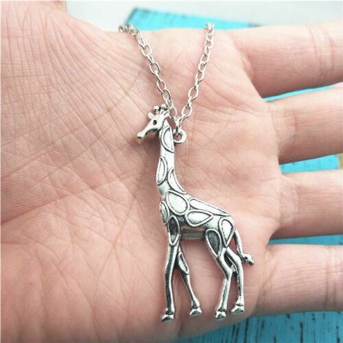 Silver giraffe pendant necklace on a hand against a blue background