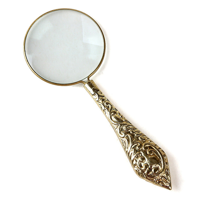 Decorative magnifying glass with ornate handle on a white background