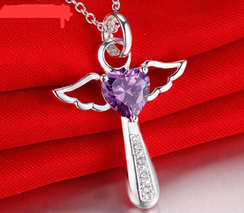 Silver angel pendant with a purple heart-shaped gem on a red fabric background