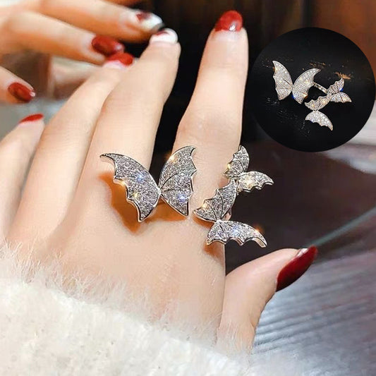 Silver butterfly-shaped ring on a finger with a close-up inset of the ring.