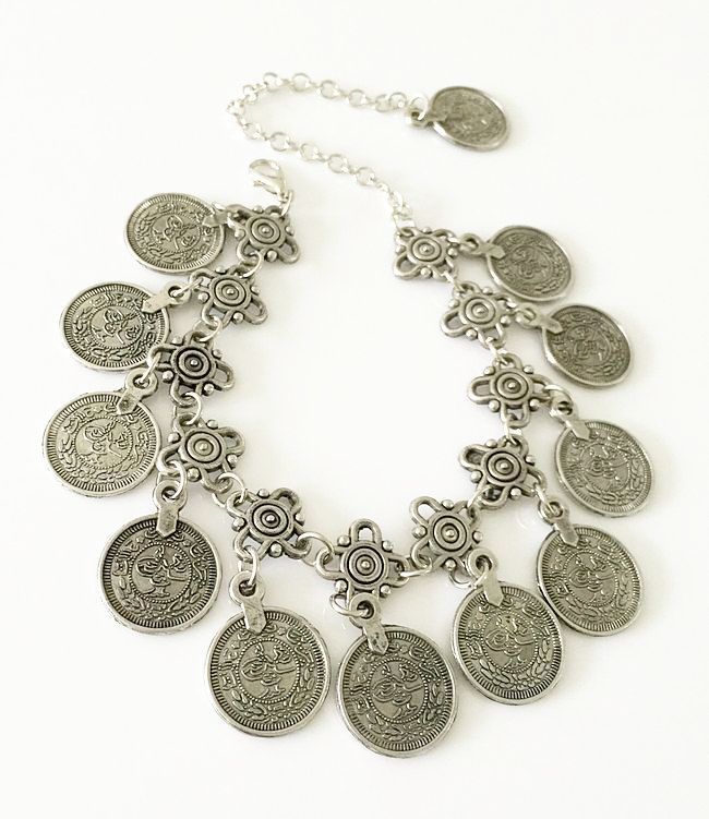 Silver necklace with coin charms on a white background