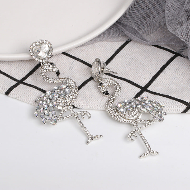 Flamingo-shaped earrings with rhinestone details on a white background