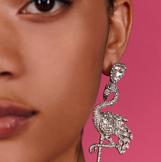 Close-up of a woman wearing a sparkling earring against a pink background