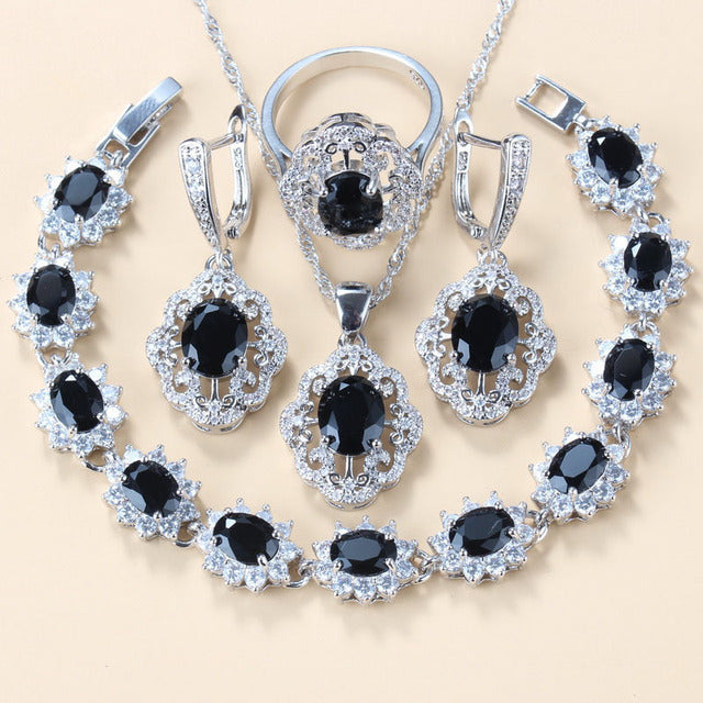 Jewelry set with black gemstones and silver accents on a beige background