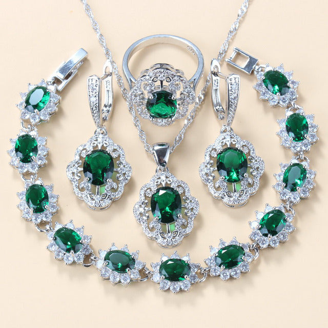 Set of green gemstone jewelry including necklace, earrings, and ring on a beige background