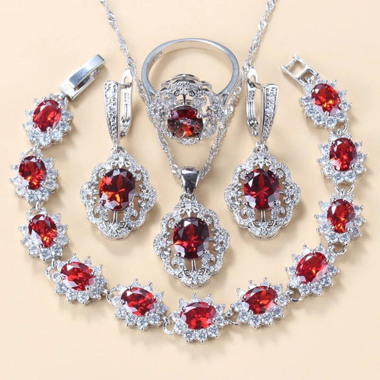 Silver jewelry set with red gemstones on a beige background
