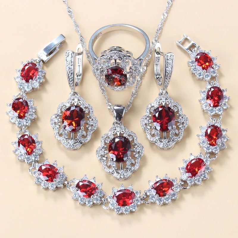 Silver jewelry set with red gemstones on a beige background