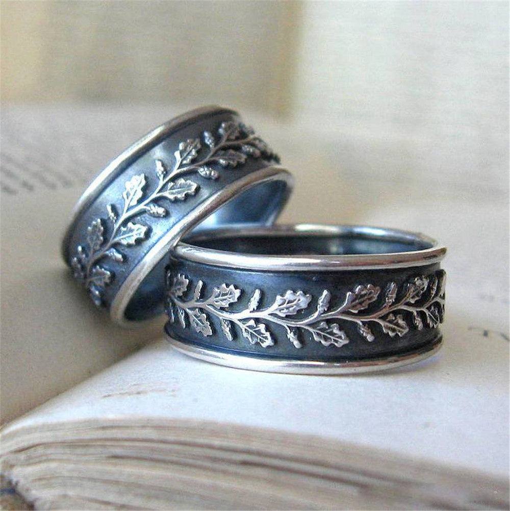 Two silver rings with leaf patterns on a textured surface