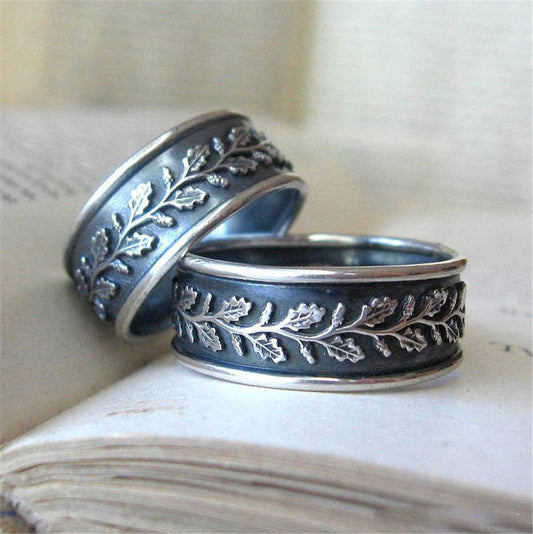 Two silver rings with leaf patterns on a textured surface