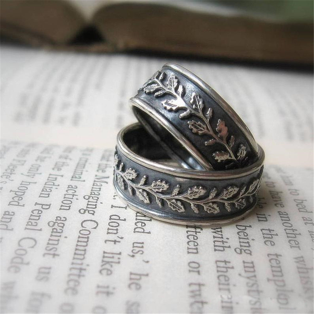 Two silver rings with leaf patterns on an open book