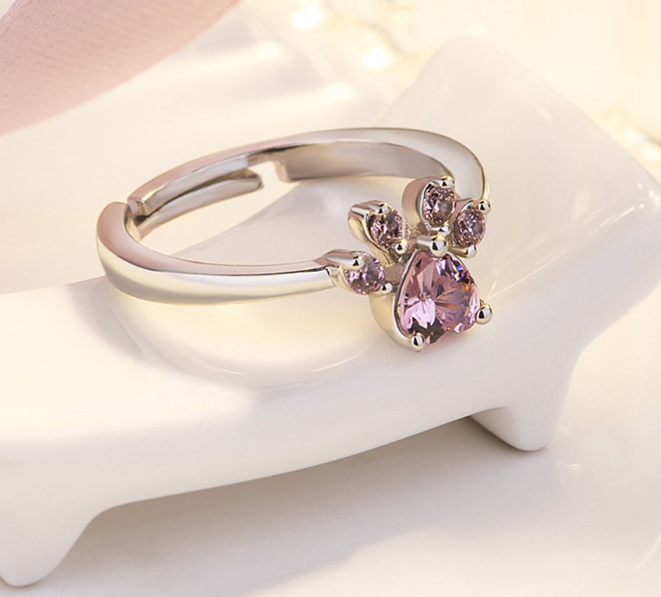 Gold ring with pink gemstones on a white surface