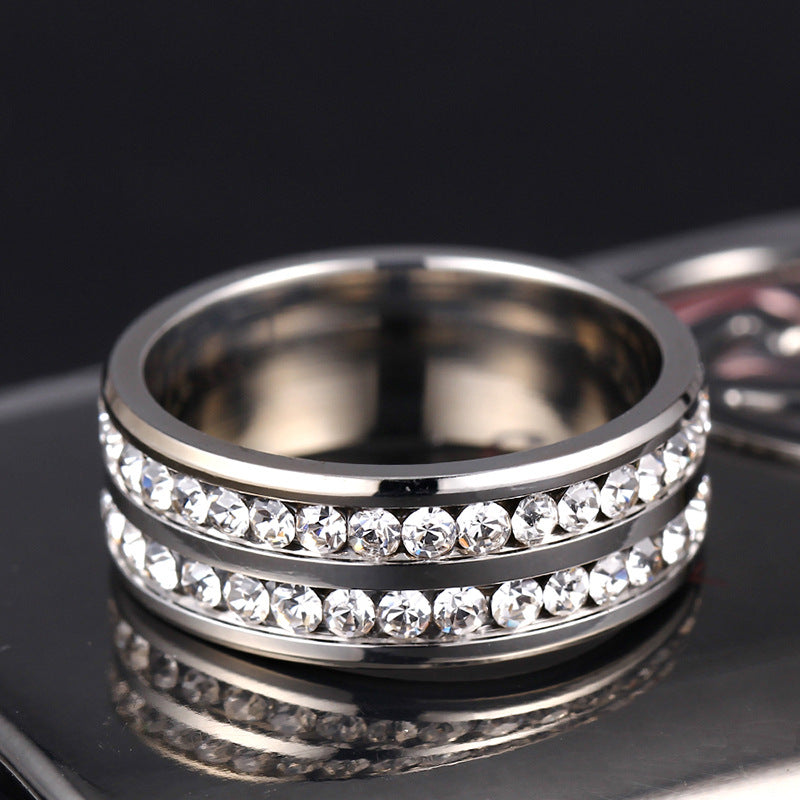 Silver ring with embedded crystals on a reflective surface
