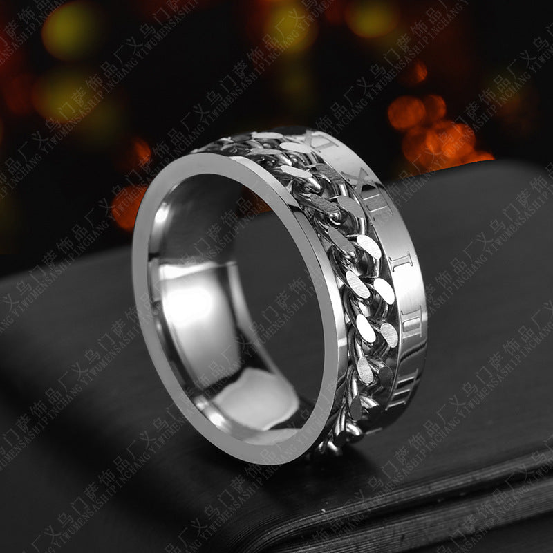 Silver chain ring on a dark surface with blurred lights in the background