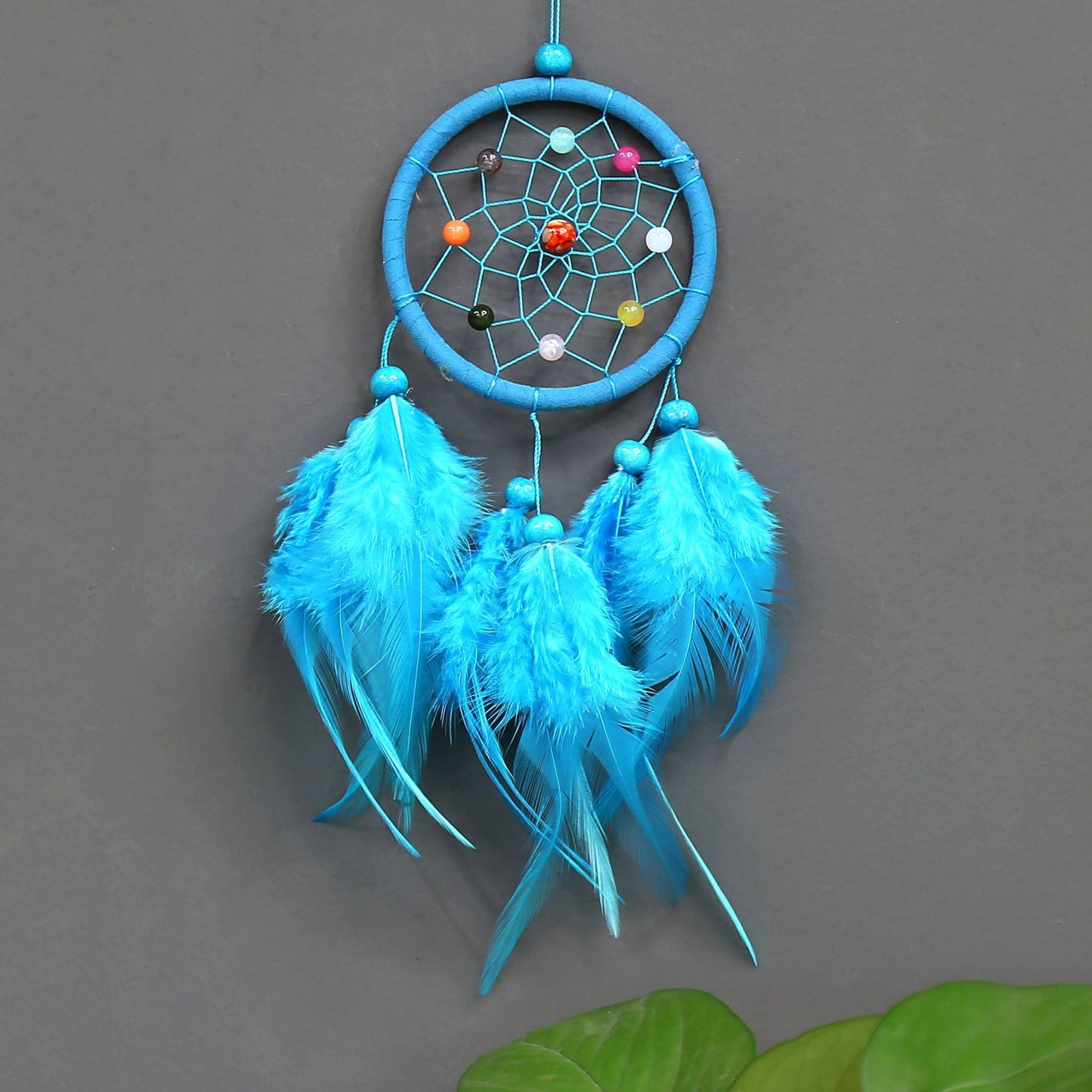 Blue dreamcatcher with feathers on a gray background