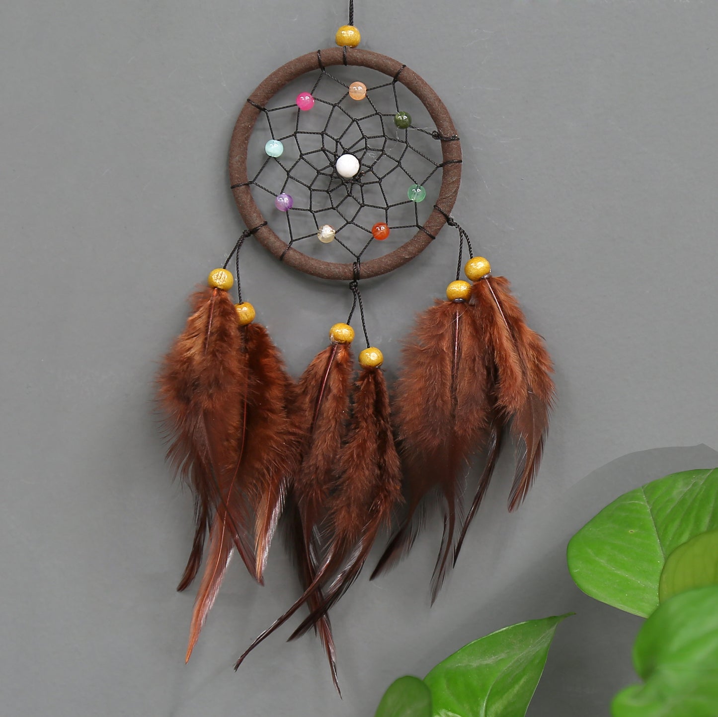 Dreamcatcher with feathers and colorful beads on a gray background