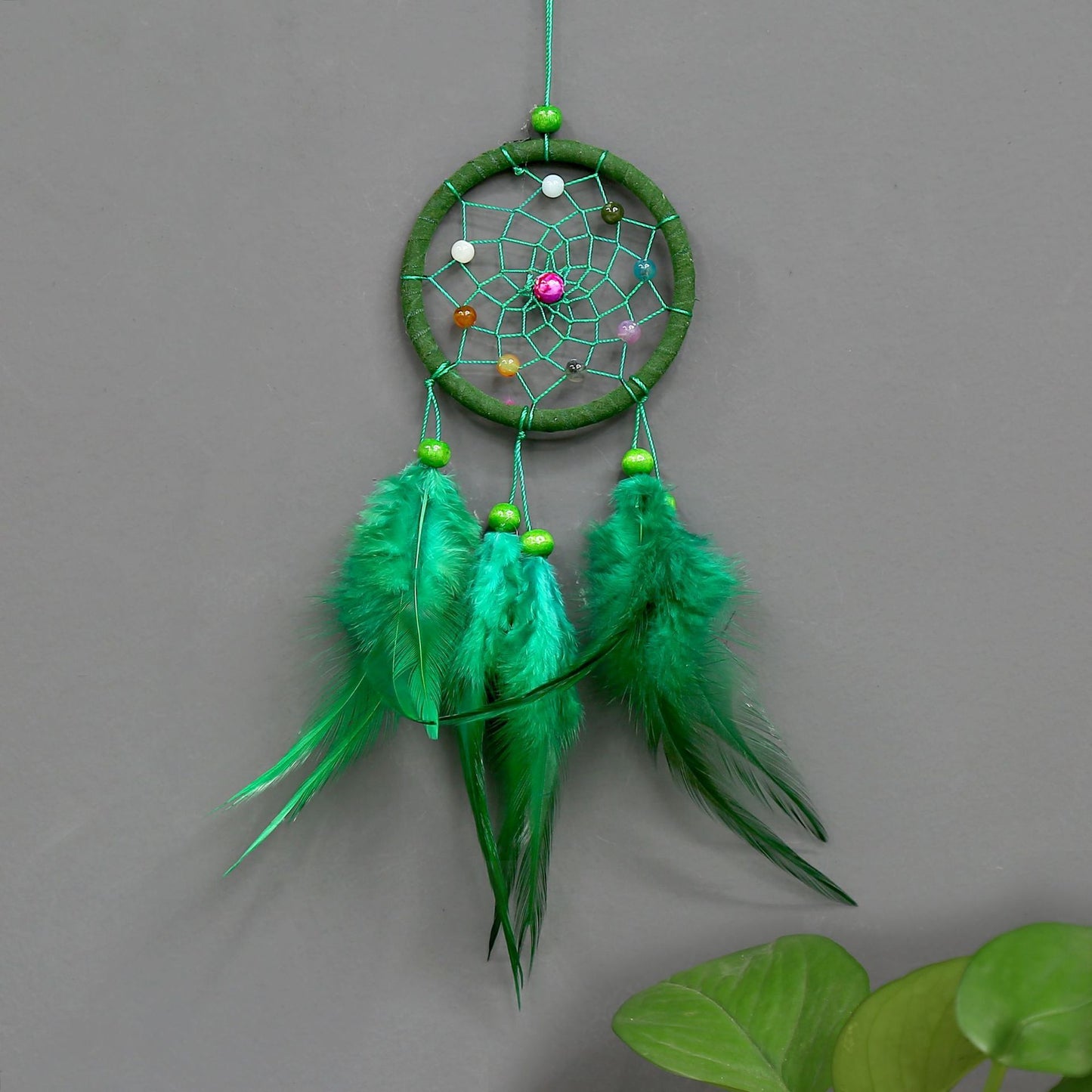 Green dreamcatcher with feathers on a gray background