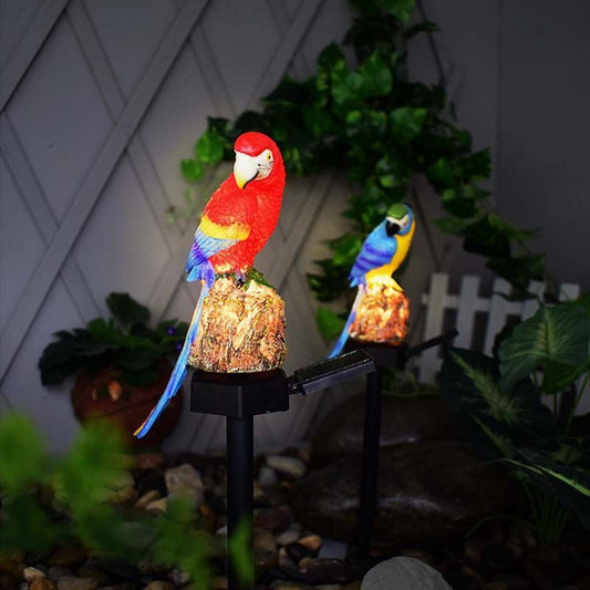 Two colorful parrot statues on stands with a garden background
