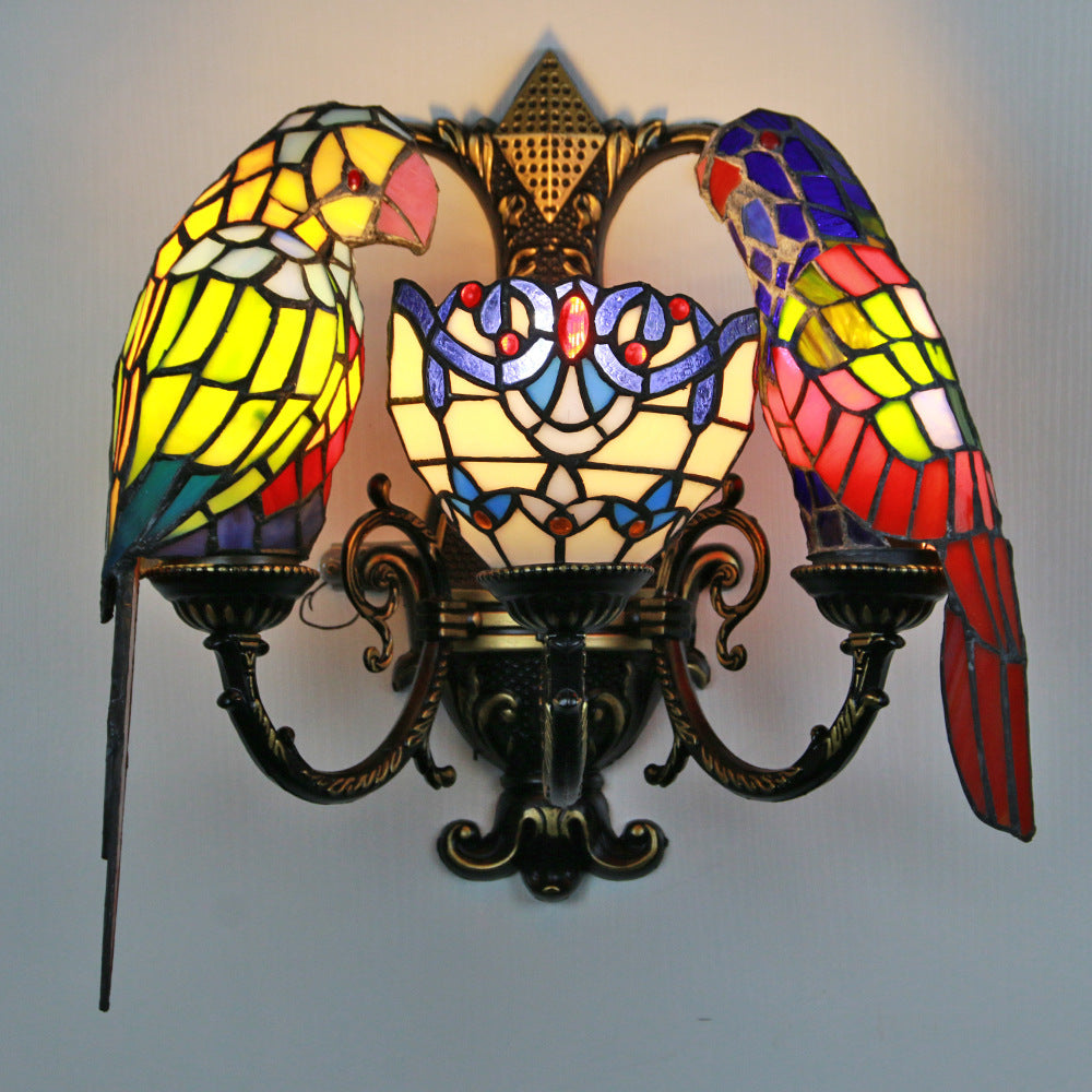 Stained glass wall sconce with parrot designs on a plain background