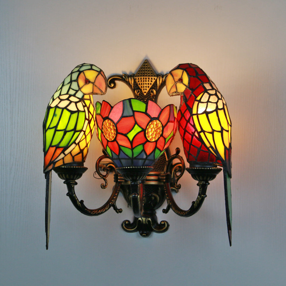 Stained glass wall sconce with parrot design on a plain background
