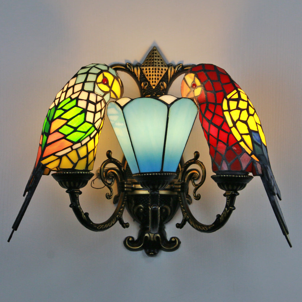 Decorative wall lamp with colorful stained glass design resembling parrots on a plain background