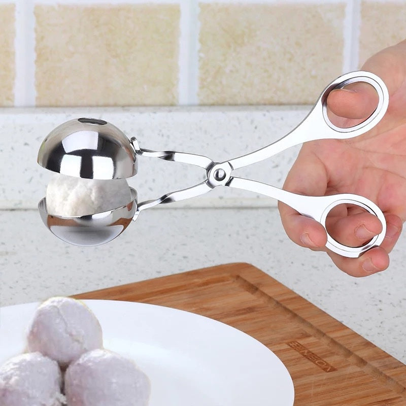 Metallic cookie scoop held by a hand with a kitchen background