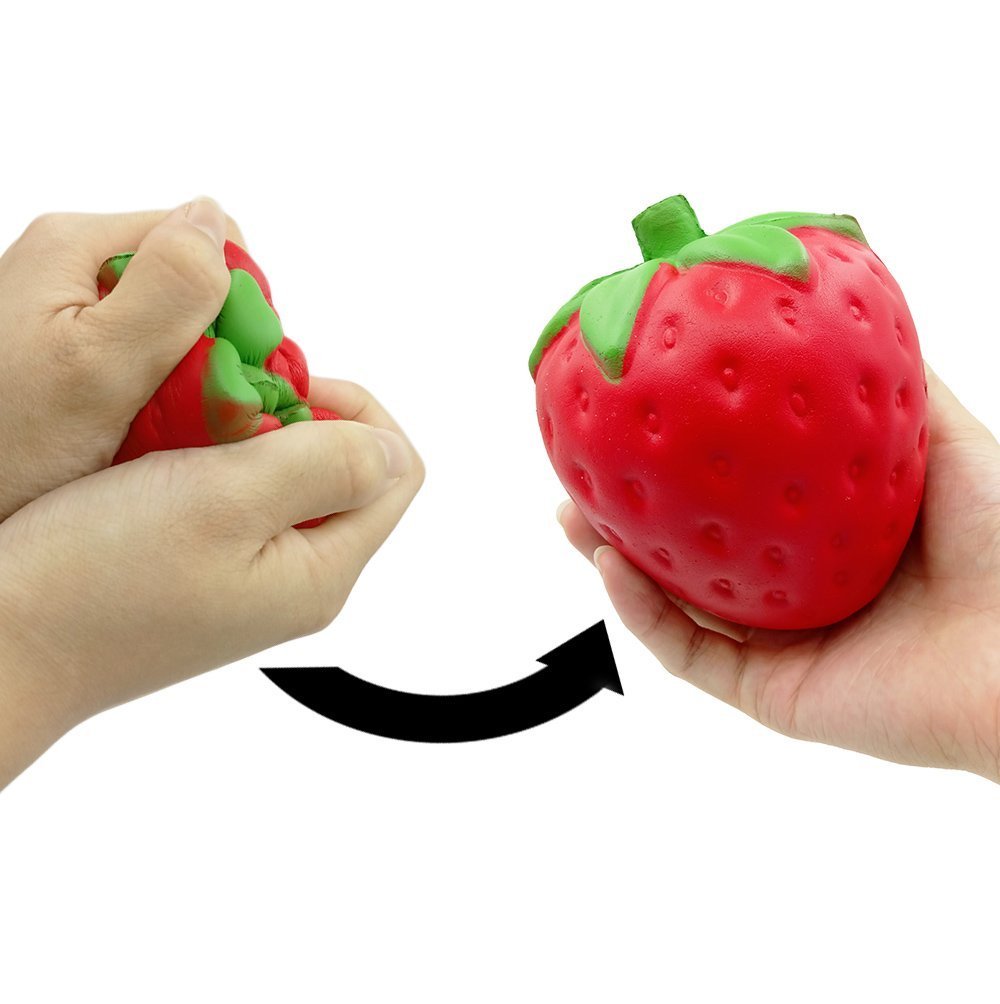 Strawberry-shaped stress ball being squeezed by two hands on a white background