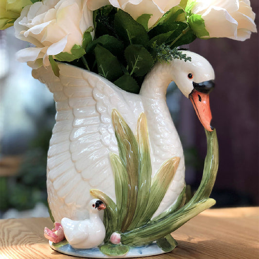 Decorative swan vase with floral elements on a wooden surface