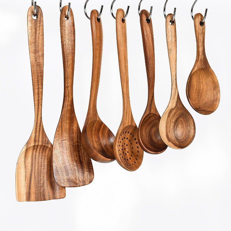 Set of wooden cooking utensils hanging on a white background