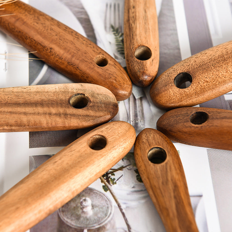 Wooden spoons with holes arranged in a circular pattern on a striped fabric background.