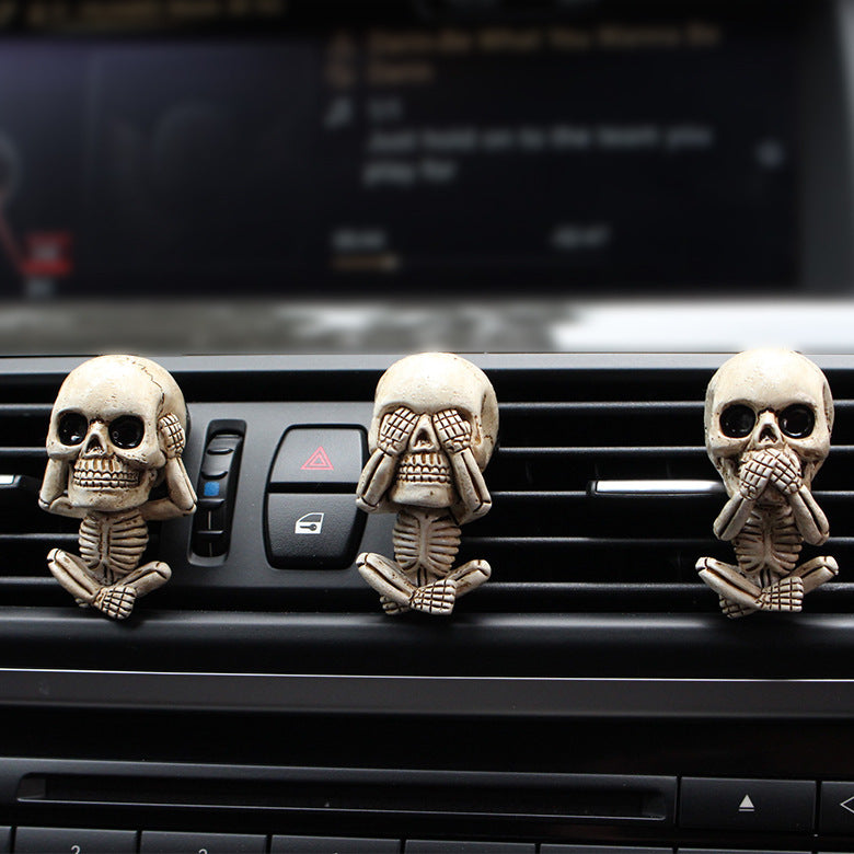 Three skull-shaped car air fresheners on a car's air vent.