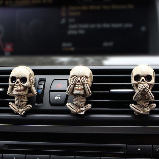 Three skull-shaped car air fresheners on a car's air vent.