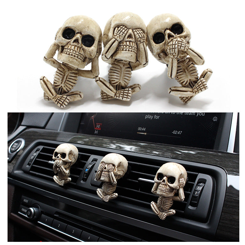 Skull-shaped car air freshener set with 'see no evil, hear no evil, speak no evil' poses on a white background.