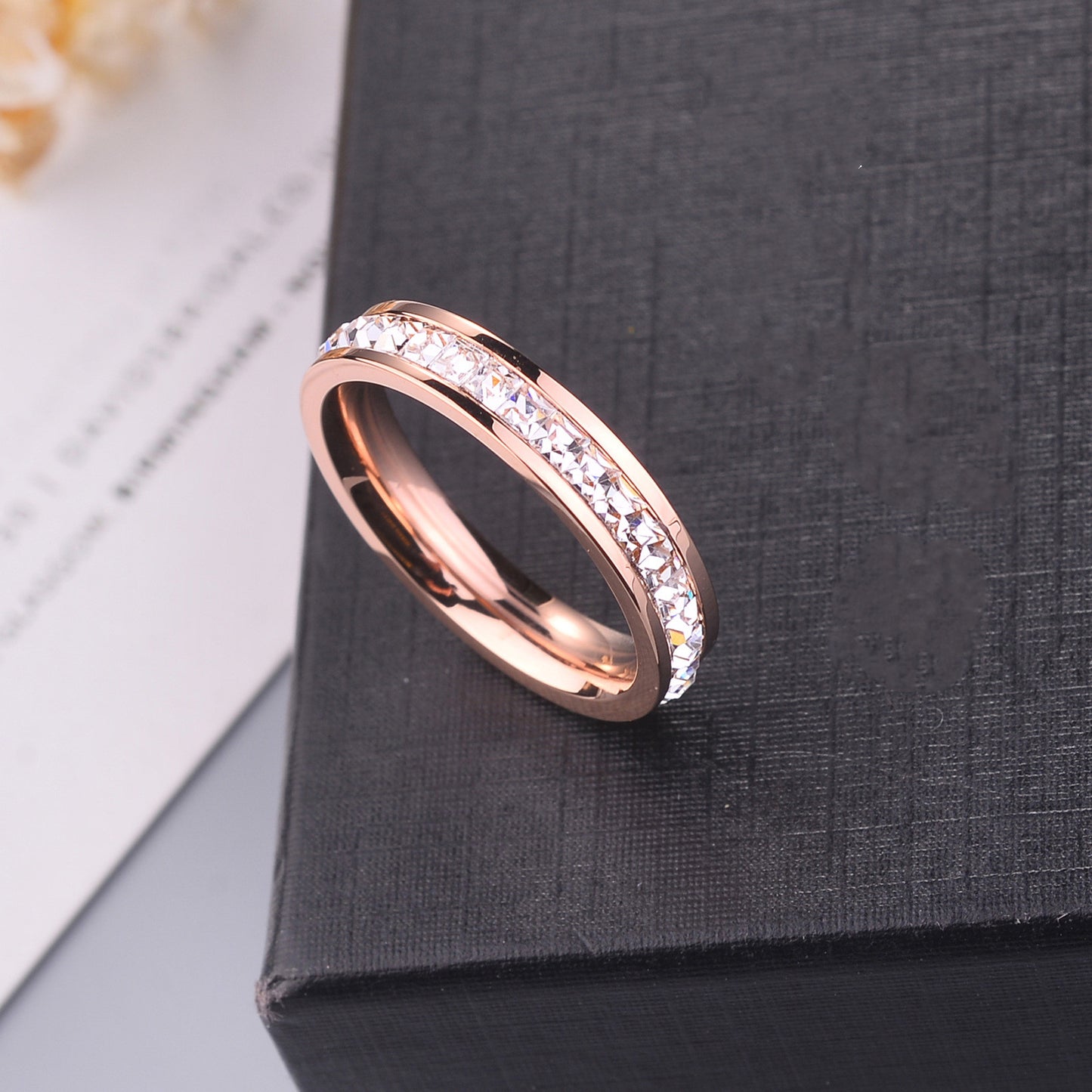 Rose gold ring with embedded stones on a dark textured surface