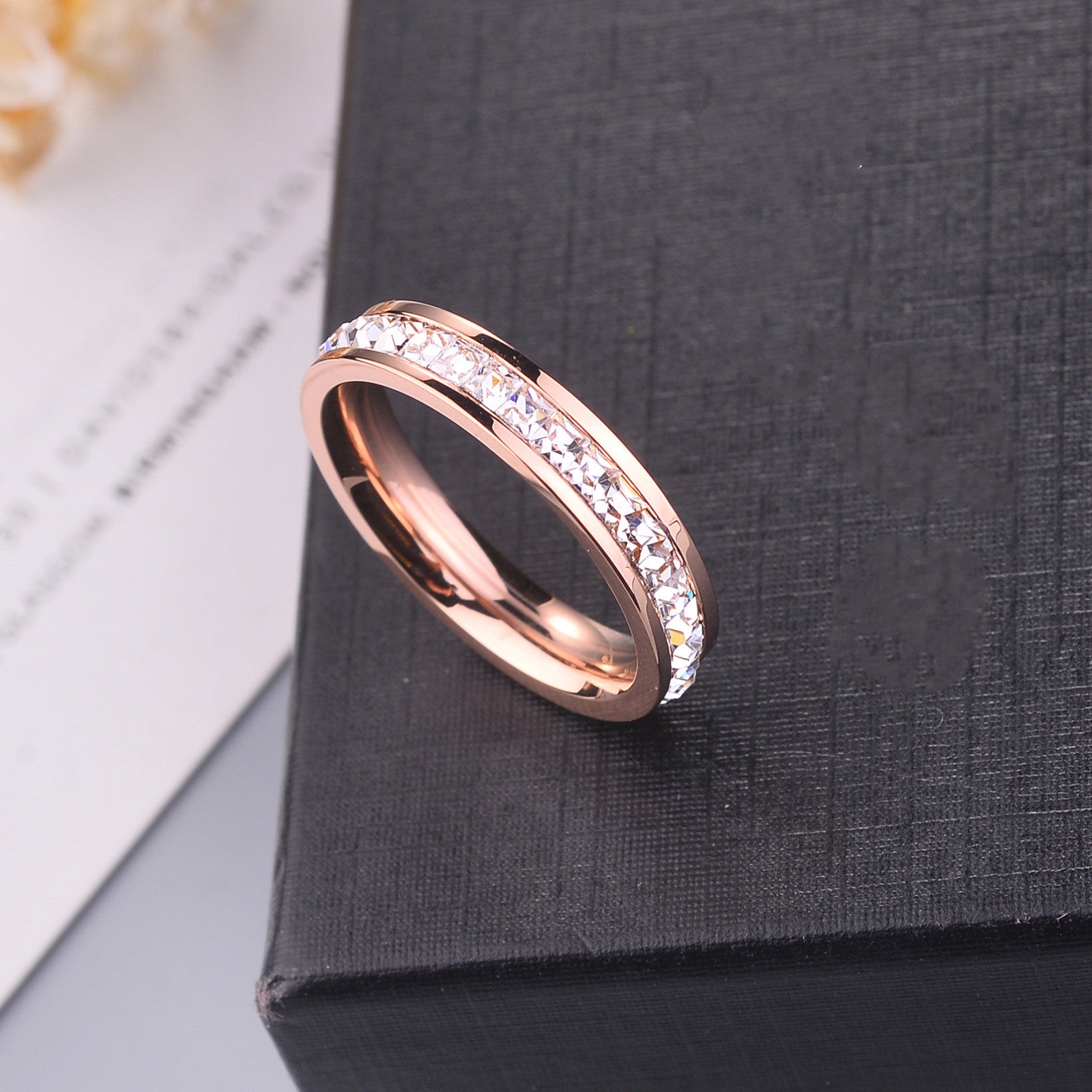 Rose gold ring with embedded stones on a dark textured surface