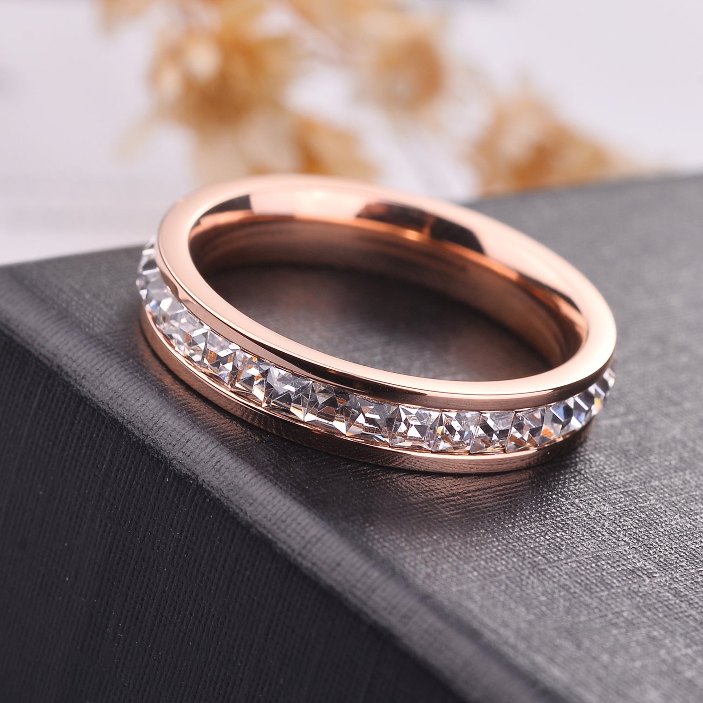 Rose gold ring with embedded diamonds on a textured surface