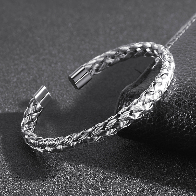 Silver braided bracelet on a textured black surface