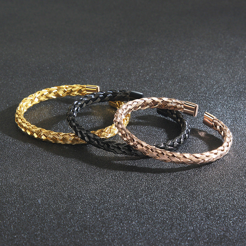 Three braided bracelets in gold, black, and rose gold on a dark surface