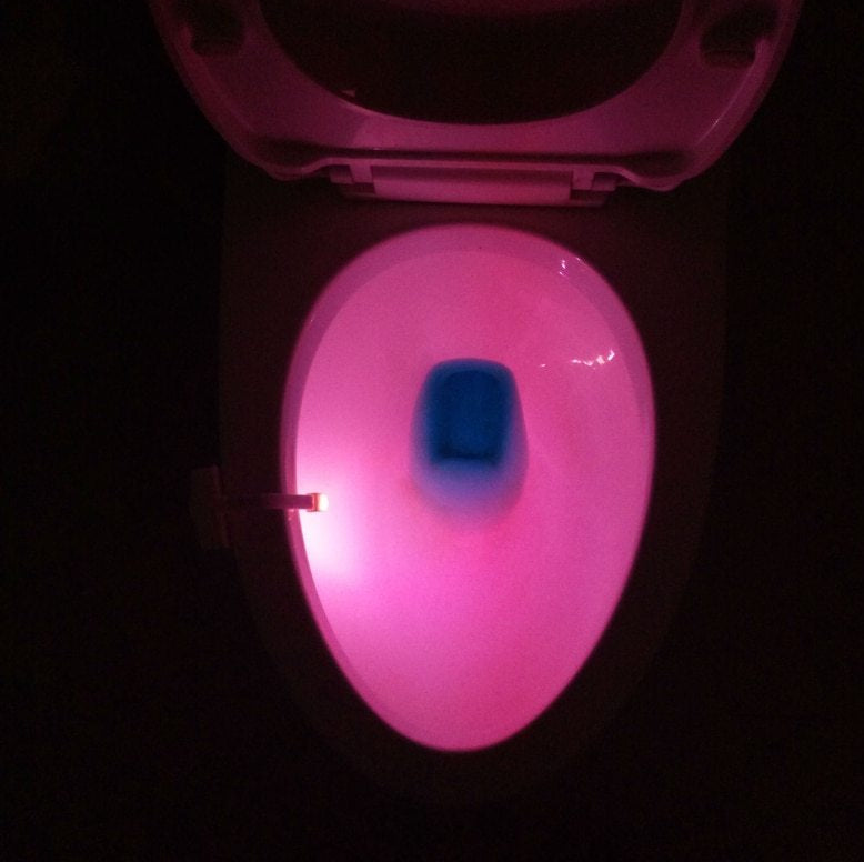 Pink glowing toilet seat with a dark background
