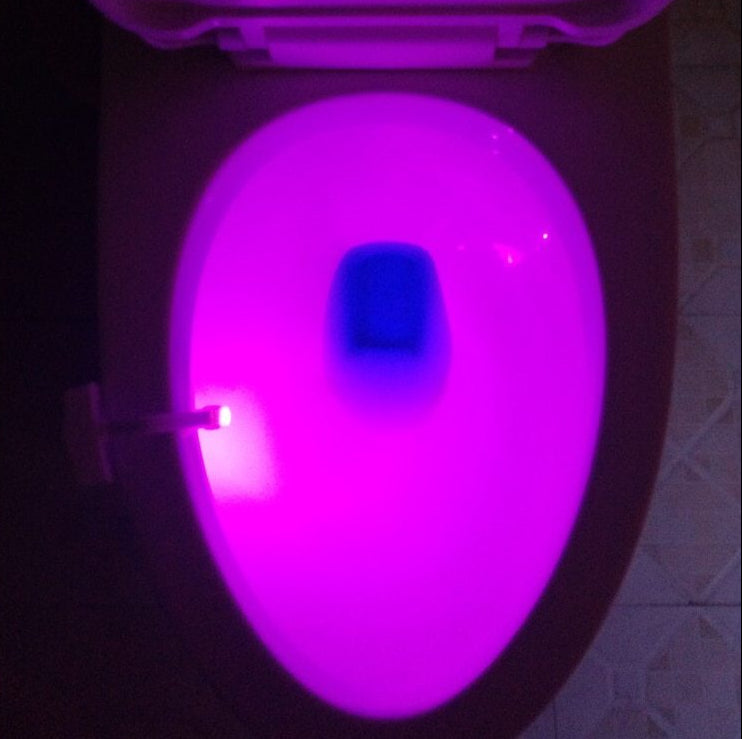 Toilet bowl with glowing purple light in a dark setting