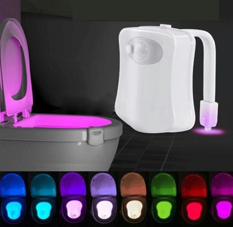 Toilet with a glowing pink seat and a white sensor unit on a dark background.