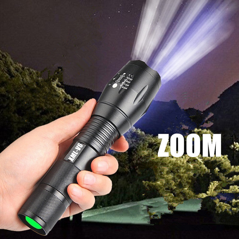 Hand holding a flashlight with a zoom feature, illuminating a night scene.