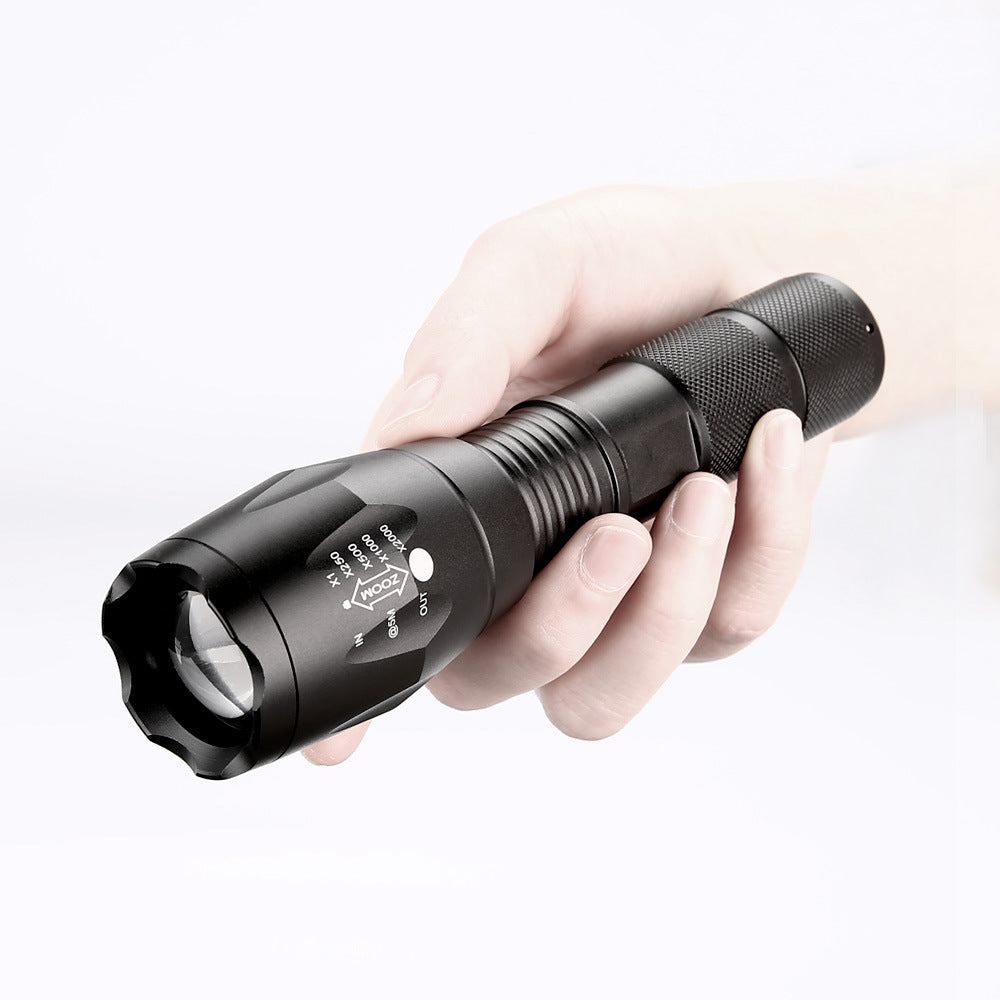 Hand holding a black flashlight against a white background
